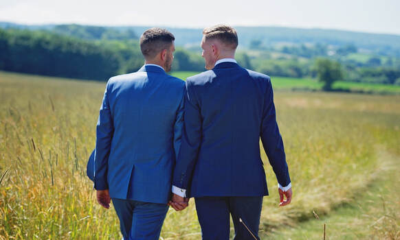 A male couple holding hands on their wedding day.